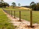 Cattle fence roll installation across rolling pasture terrain